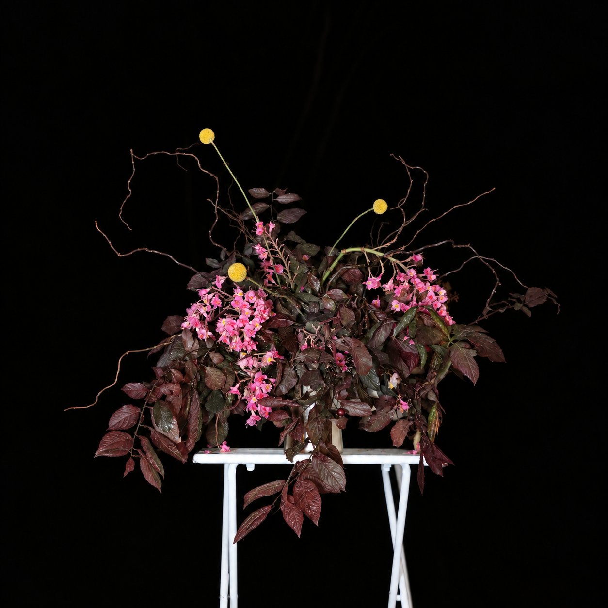 Pink and burgundy pedestal floral installation photographed in the studio.