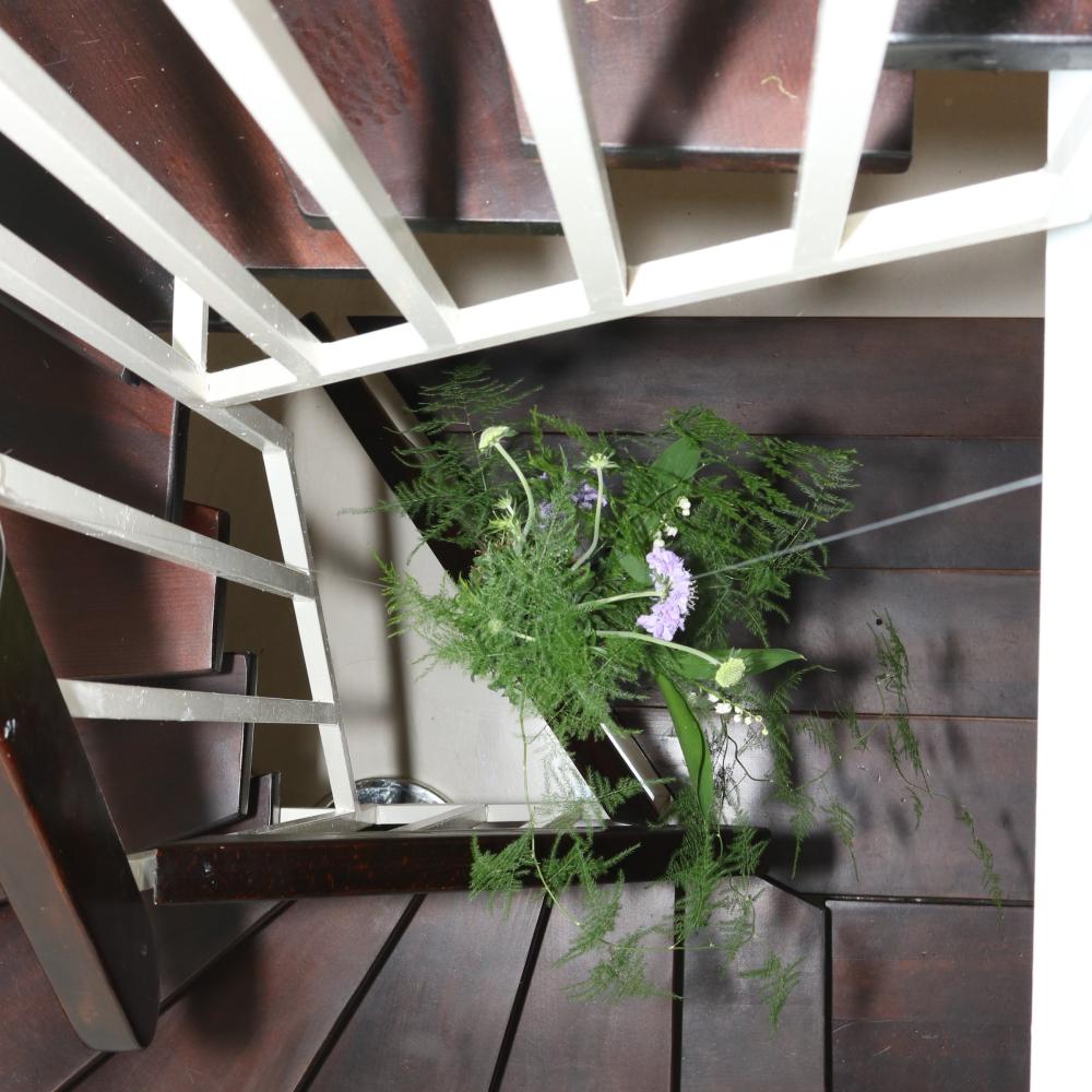 Small floral arrangement placed on a dark wood spiral staircase during installation