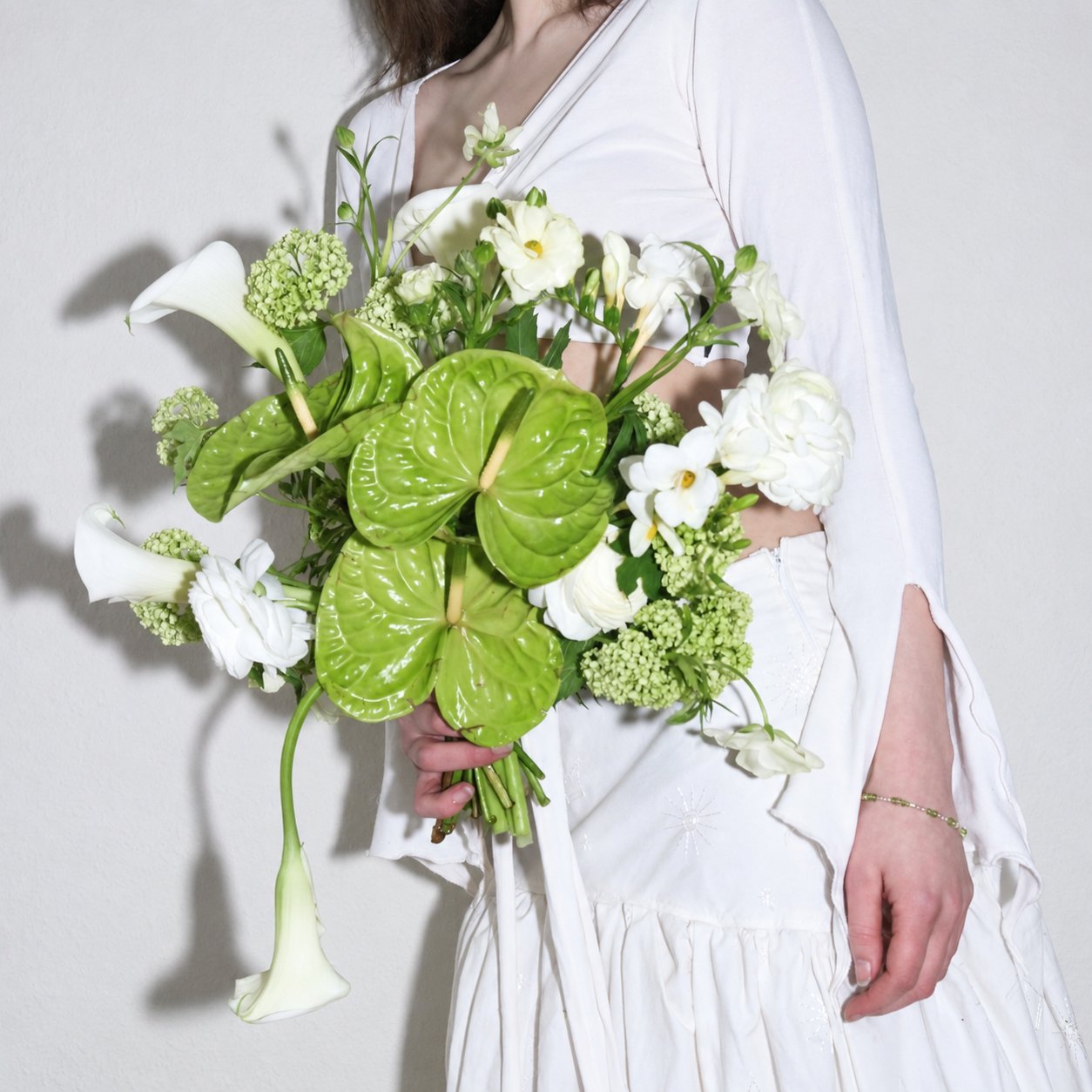 Bride holding a bouquet of green anthurium and white calla lilies for Wedding x Moyo.