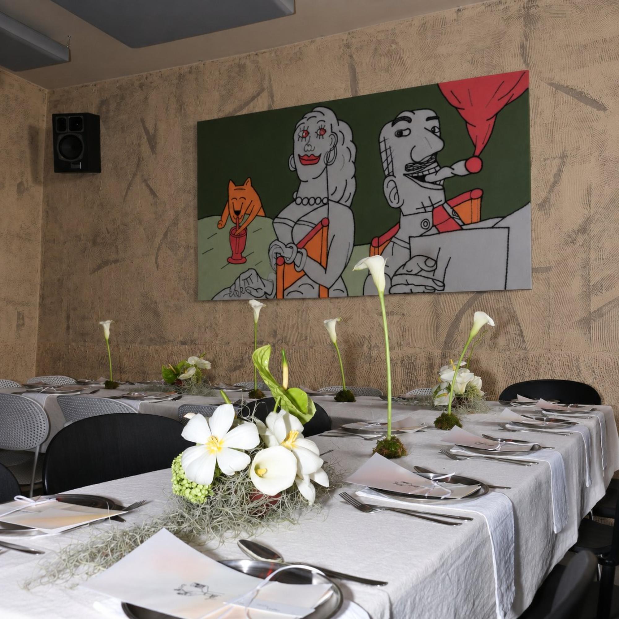 Wedding reception tablescape with calla lily centerpieces beneath a mural, place settings visible