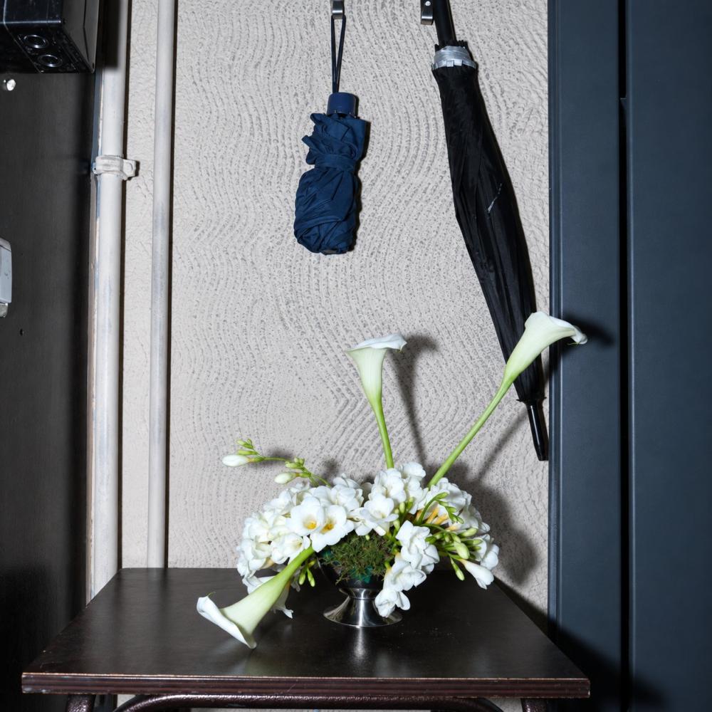 Calla lily and white freesia arrangement on an entryway table near hanging umbrellas